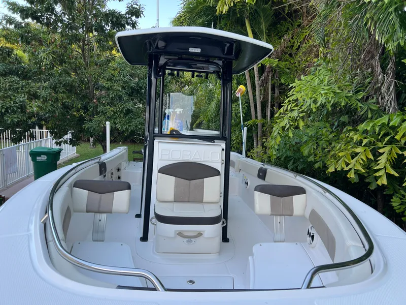 Slide: The Image of 2018 Robalo R242 Center Console boat with seating, surrounded by lush greenery. - 6