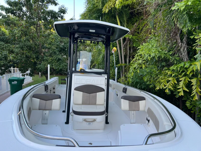 Slide: The Image of 2018 Robalo R242 Center Console boat with seating, surrounded by lush greenery. - 8