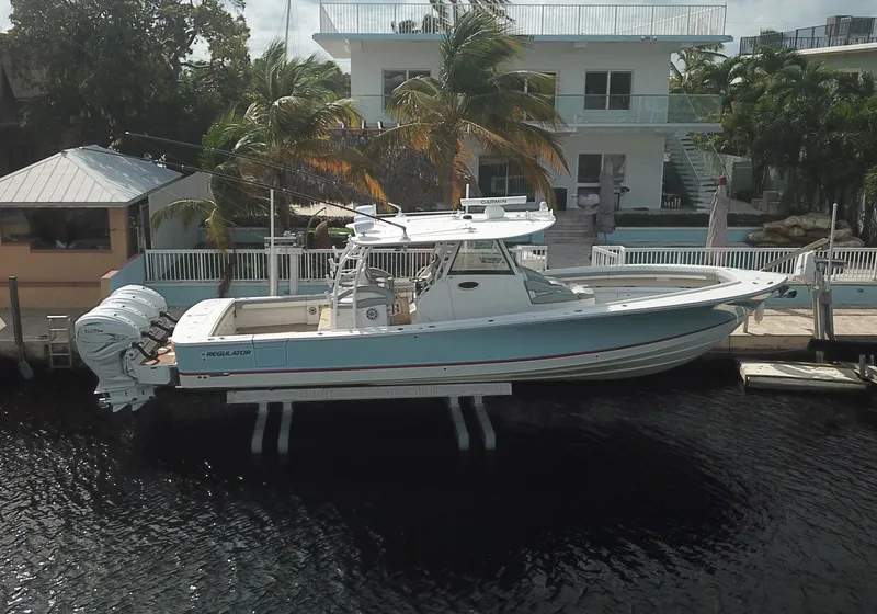 Slide: The Image of 2022 Regulator 41 boat docked near waterfront home with palm trees. - 0