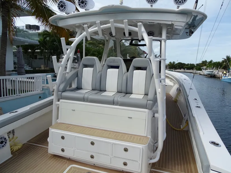 Slide: The Image of 2022 Regulator 41 boat with cushioned seating and storage, docked by palm trees. - 15