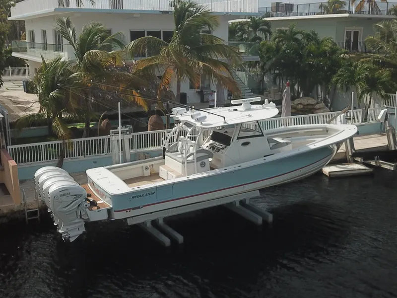 Slide: The Image of 2022 Regulator 41 boat docked near waterfront homes with palm trees. - 2