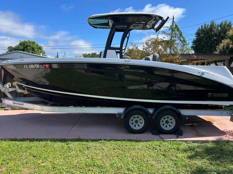 Slide: The Image of 2021 Yamaha Boats FSH 255 Sport E on a trailer in a driveway. - 1