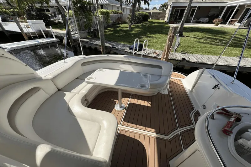 Slide: The Image of 2005 Sea Ray 340 Sundancer boat interior with seating and table, docked by a canal. - 10