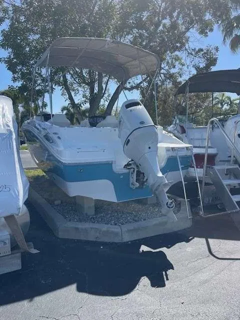 Slide: The Image of 2024 Hurricane 218 SS boat with outboard motor and canopy in a parking lot. - 2