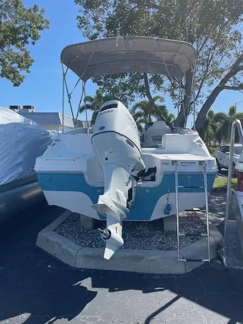 Slide: The Image of 2024 Hurricane 218 SS boat with outboard motor and canopy in a parking lot. - 9