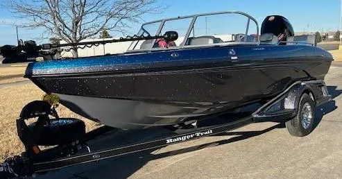 Slide: The Image of 2024 Ranger 1880MS boat on trailer, black and blue, parked outdoors. - 0