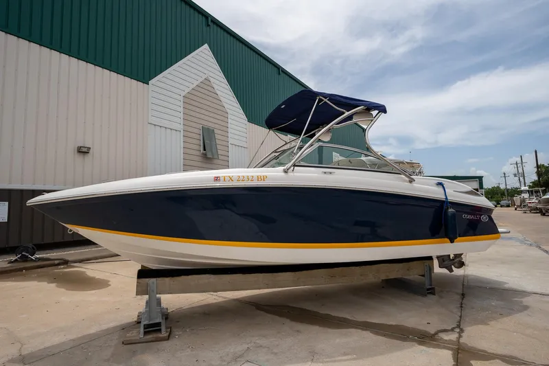 Slide: The Image of 2011 Cobalt 242 boat with blue hull and yellow stripe on a stand. - 3