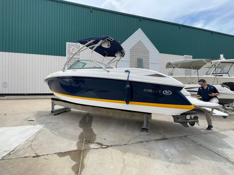 Slide: The Image of 2011 Cobalt 242 boat on a stand outside a green and white building. - 40