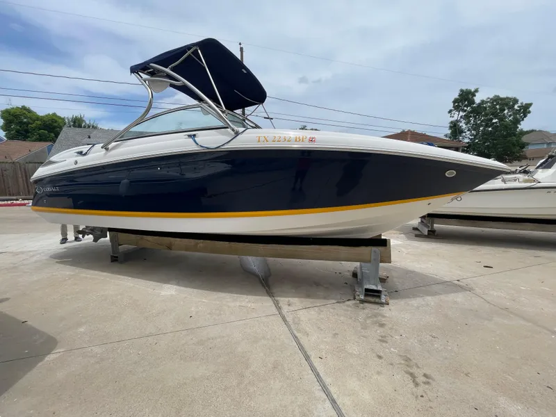 Slide: The Image of 2011 Cobalt 242 boat with blue hull and canopy on a stand. - 44