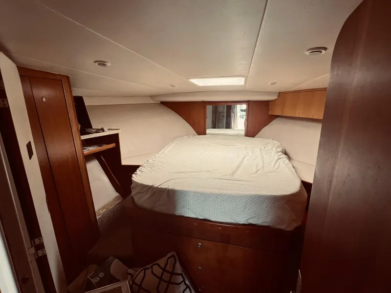 Slide: The Image of 1999 Luhrs 360 Sportfish cabin with bed, wooden cabinets, and overhead lighting. - 24