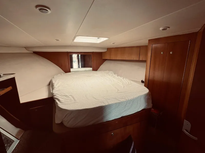Slide: The Image of 1999 Luhrs 360 Sportfish cabin with bed, wooden cabinets, and overhead lighting. - 26