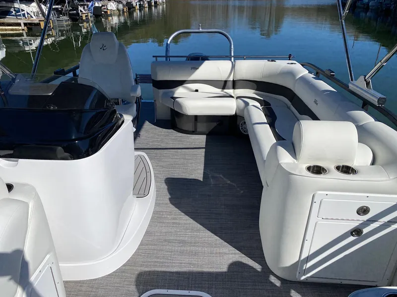 Slide: The Image of 2024 JC Neptoon Sport 23TT pontoon boat interior with white seating and lake view. - 19