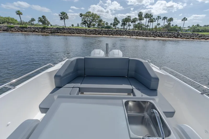 Slide: The Image of 2024 Nimbus Tender 9 #130 boat with spacious seating and sink, docked by a scenic shoreline. - 9