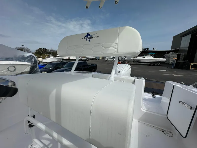 Slide: The Image of 2024 Aquasport 2200 CC boat with white seating and logo, docked at a marina. - 6