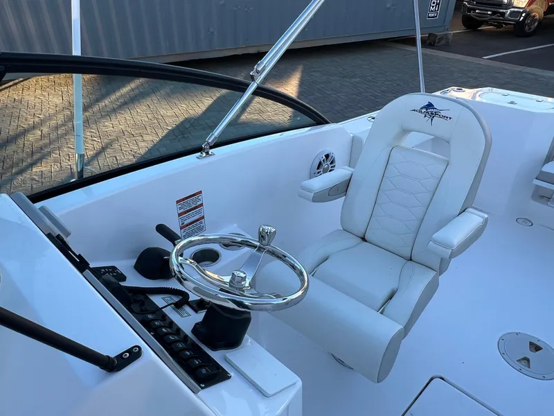 Slide: The Image of 2024 Aquasport 2200 DC boat cockpit with steering wheel and captain's chair. - 12