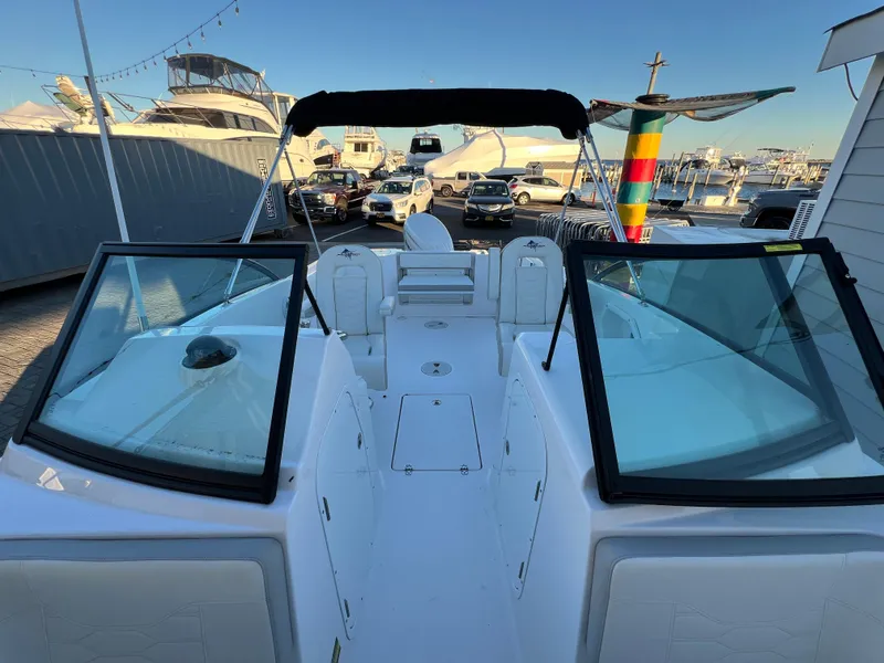 Slide: The Image of 2024 Aquasport 2200 DC boat with open deck and dual windshields at a marina. - 14