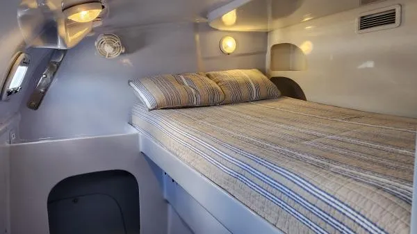 Slide: The Image of Cozy cabin interior of 1991 Custom Morelli-Miller with striped bedding and ambient lighting. - 18