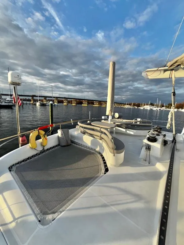 Slide: The Image of Catamaran deck with seating, netting, and marina view under cloudy sky. Custom Morelli-Miller, 1991. - 33