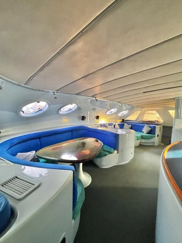 Slide: The Image of Luxurious 1991 Custom Morelli-Miller yacht interior with blue seating and oval windows. - 4