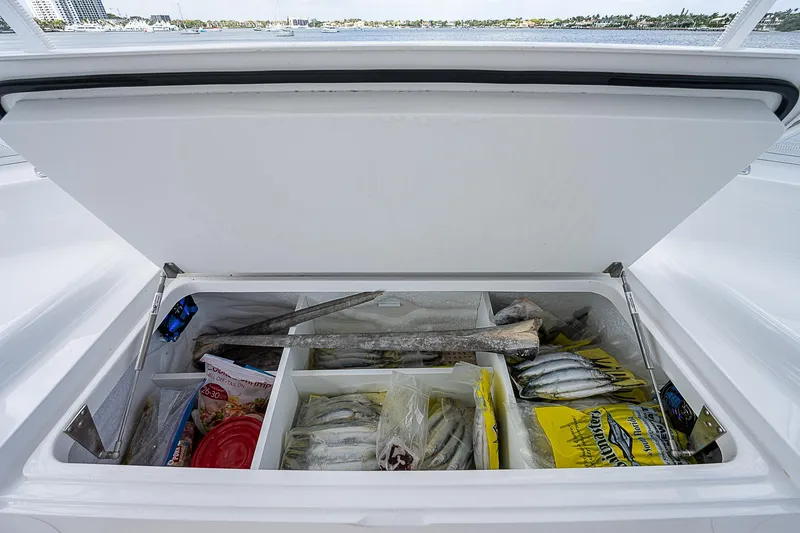Slide: The Image of Open storage compartment on a 2020 Viking 68 Convertible boat filled with fishing supplies. - 23