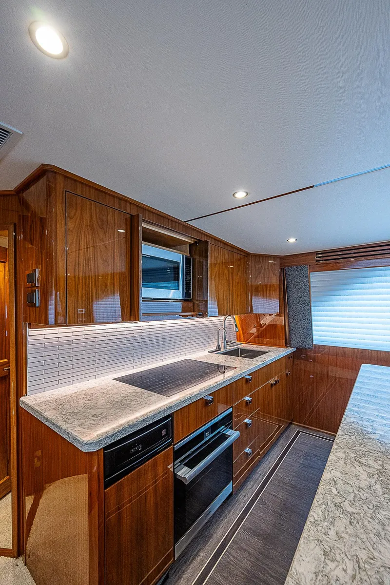 Slide: The Image of Modern kitchen in 2020 Viking 68 Convertible yacht with sleek countertops and wooden cabinetry. - 31