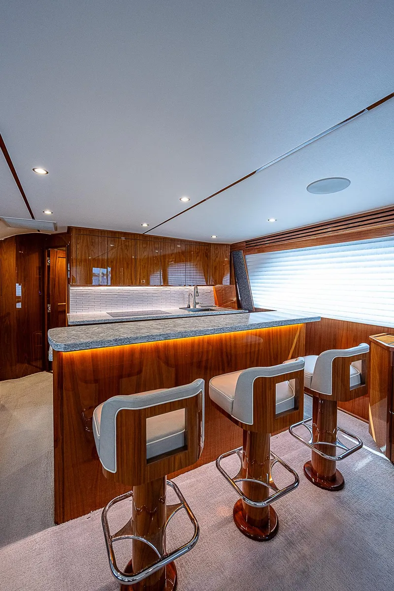 Slide: The Image of Interior of 2020 Viking 68 Convertible yacht with bar stools and wooden finishes. - 34