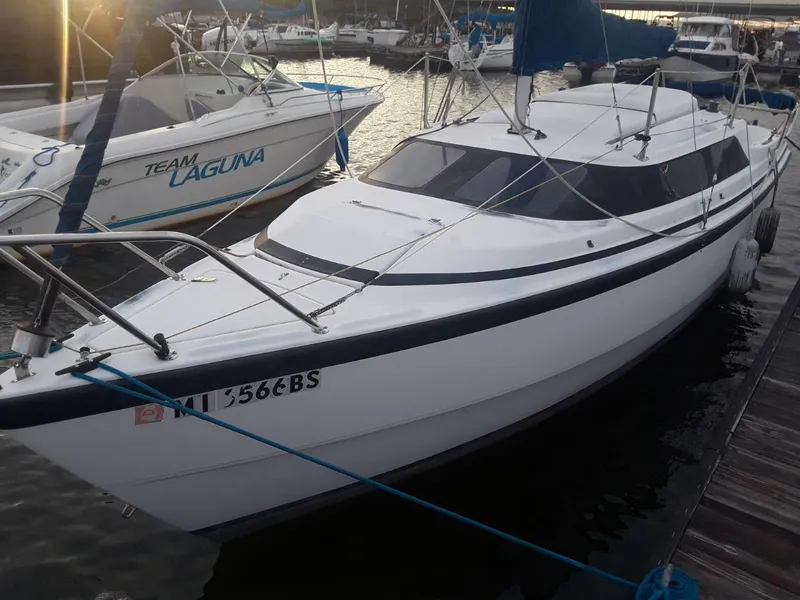 Slide: The Image of 1996 MacGregor 26 "X" sailboat docked at marina, white hull, blue trim, overcast sky. - 2