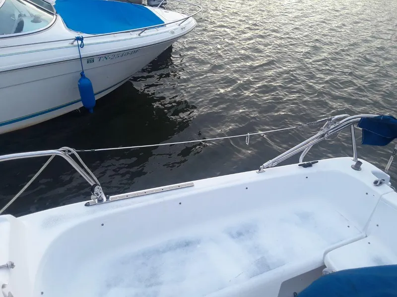 Slide: The Image of 1996 MacGregor 26 "X" sailboat docked on calm water, adjacent to another boat. - 23