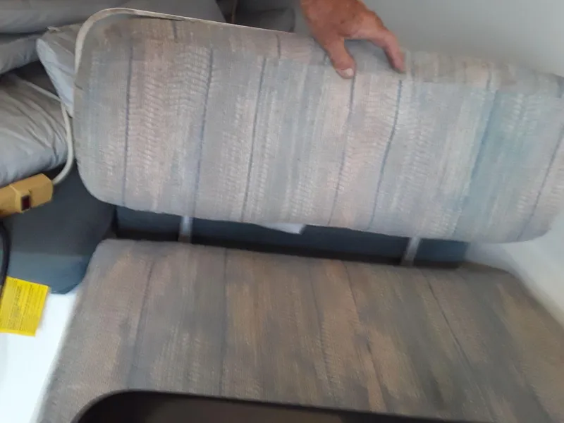 Slide: The Image of Cushioned seating inside 1996 MacGregor 26 "X" boat, with hand lifting seat cover. - 32