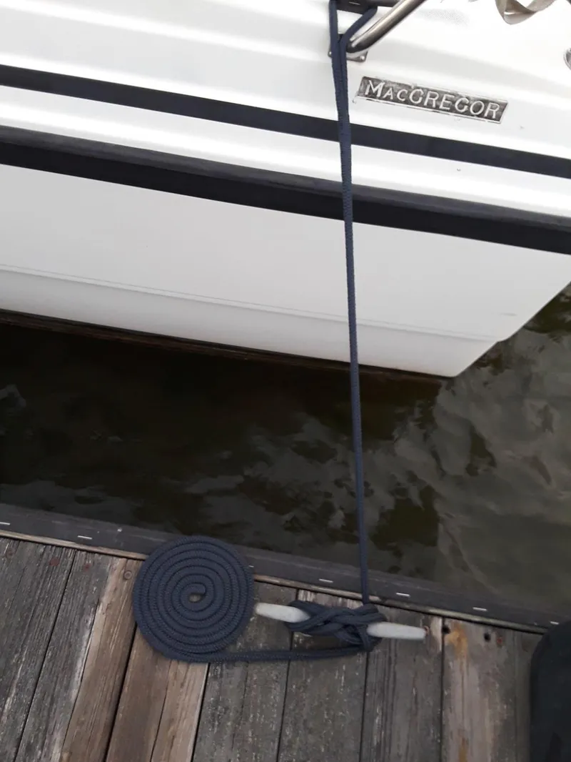 Slide: The Image of 1996 MacGregor 26 "X" sailboat docked with coiled rope on wooden pier. - 47