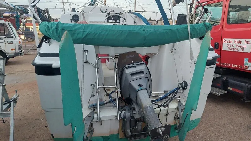 Slide: The Image of 1996 MacGregor 26 "X" sailboat with outboard motor, docked near trucks. - 48