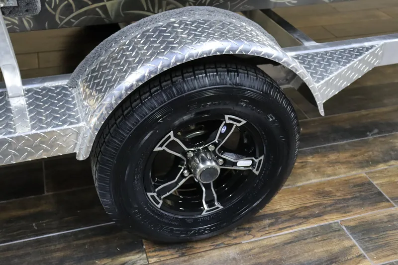 Slide: The Image of 2024 Excel 1651 Viper trailer wheel with diamond plate fender on wooden floor. - 11