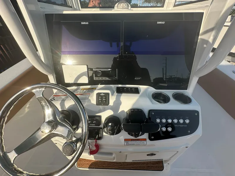 Slide: The Image of 2024 NauticStar 292 Legacy boat helm with dual Simrad displays and stainless steel steering wheel. - 14