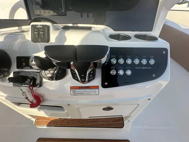 Slide: The Image of 2024 NauticStar 292 Legacy boat control panel with throttle, switches, and cup holders. - 15