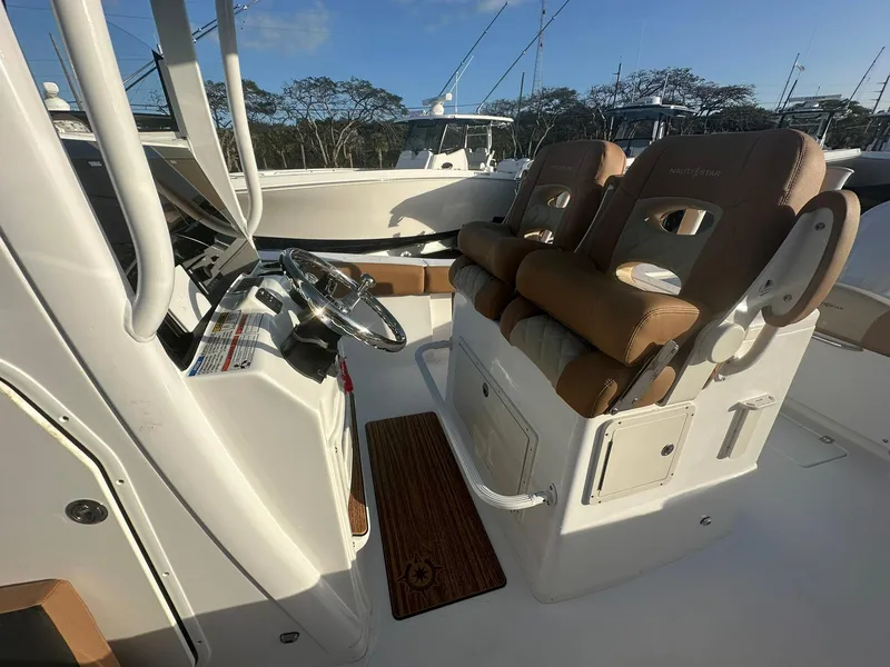 Slide: The Image of 2024 NauticStar 292 Legacy boat interior with dual captain's chairs and steering console. - 20