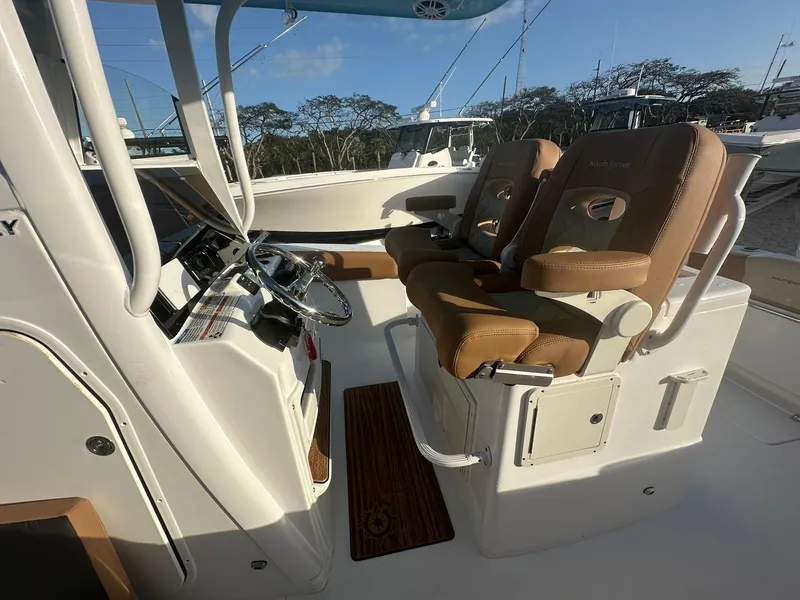 Slide: The Image of 2024 NauticStar 292 Legacy boat interior with dual captain's chairs and steering console. - 21