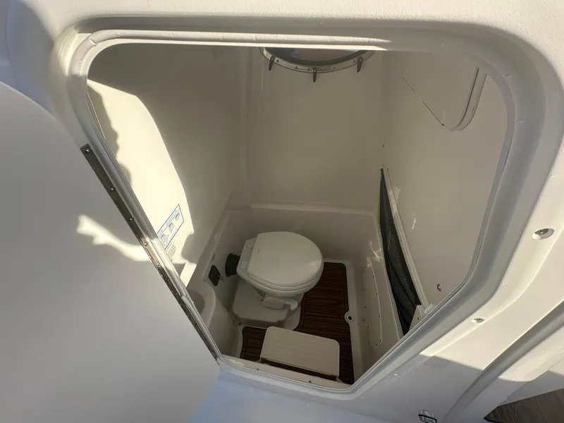 Slide: The Image of 2024 NauticStar 292 Legacy boat interior bathroom with toilet and wooden floor. - 23