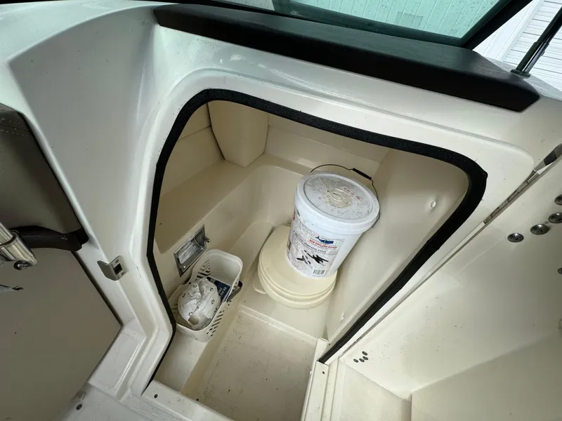 Slide: The Image of 2013 Sea Ray 250 SLX boat interior storage compartment with bucket and cleaning supplies. - 12