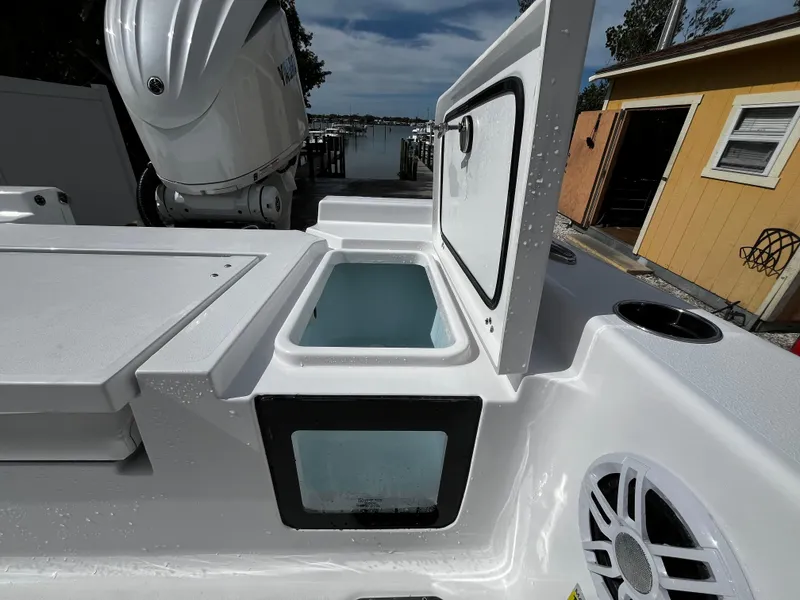 Slide: The Image of 2024 Sportsman Masters 247OE Bay Boat with open storage compartment and docked engine. - 10