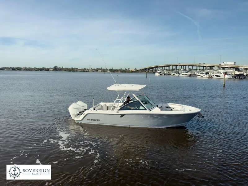Slide: The Image of 2024 Blackfin 252 DC boat cruising on a calm river near a bridge. - 1
