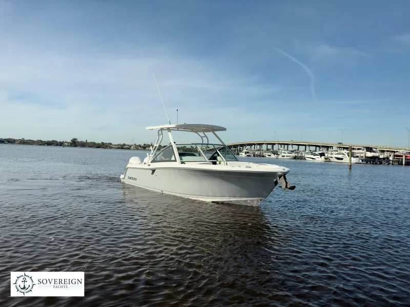 Slide: The Image of 2024 Blackfin 252 DC boat on calm water near a marina, Sovereign Yachts logo. - 10