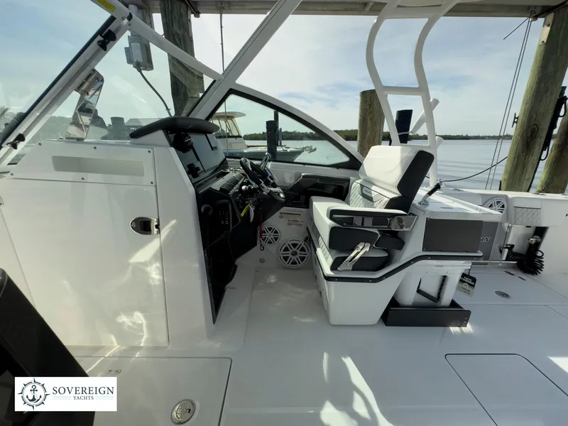 Slide: The Image of 2024 Blackfin 252 DC boat interior with helm and seating, docked by the water. - 33