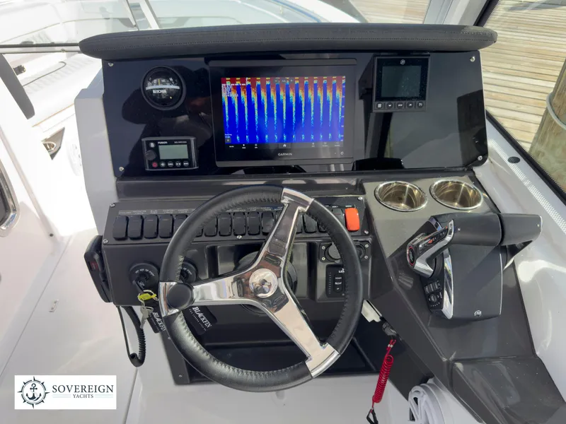 Slide: The Image of 2024 Blackfin 252 DC boat dashboard with steering wheel, navigation screen, and controls. - 36