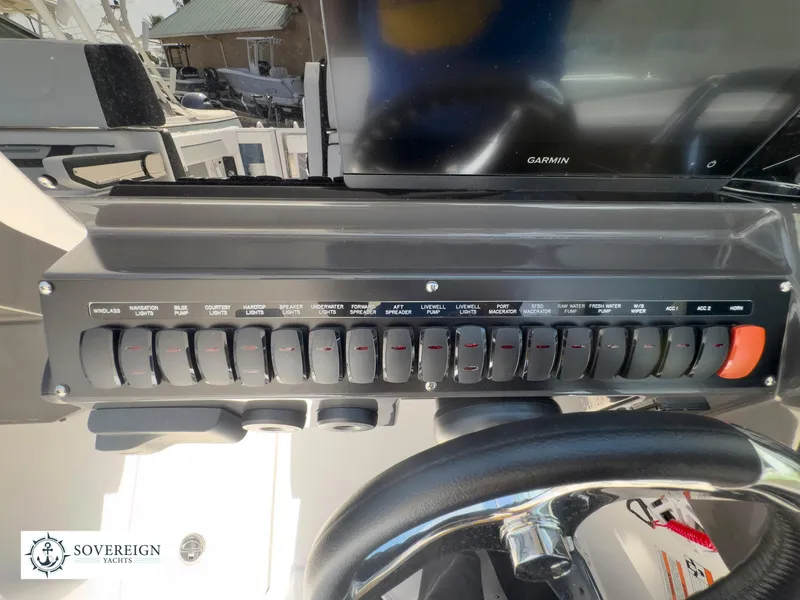 Slide: The Image of Control panel of a 2024 Blackfin 272 DC boat with various switches and Garmin display. - 32