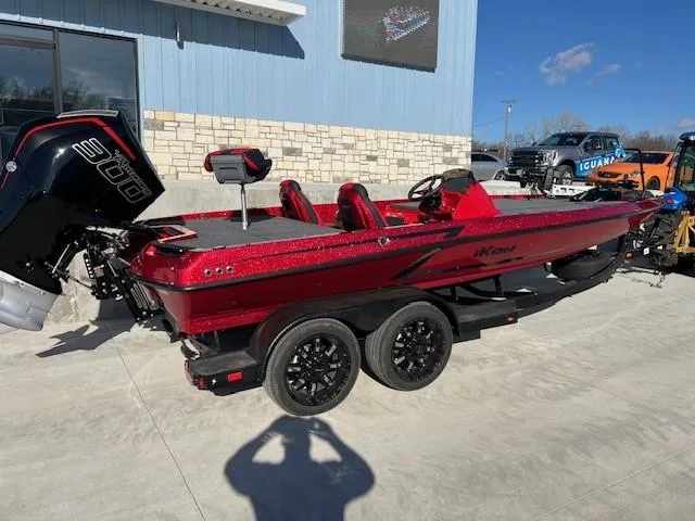 Slide: The Image of 2024 iKon LX20 red fishing boat on trailer, parked outside a building. - 2
