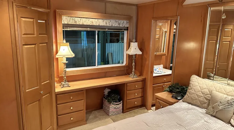 Slide: The Image of Cozy bedroom with wooden furniture, desk, lamps, and window in a 2005 Fantasy 18 x 80 model. - 4