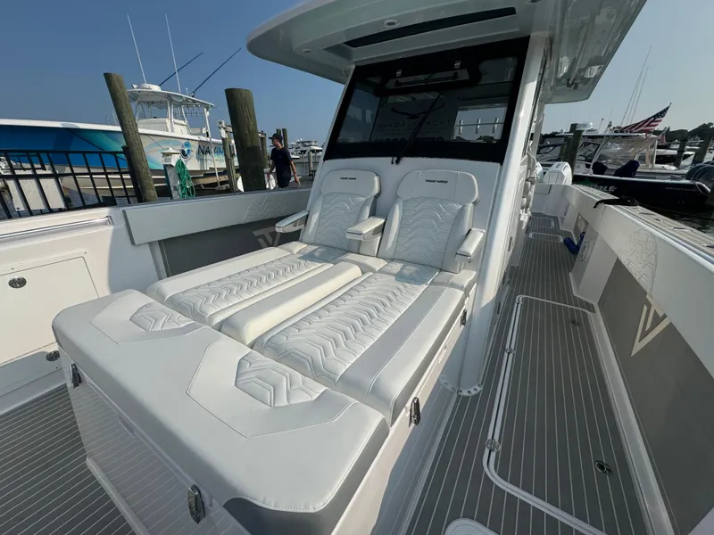 Slide: The Image of 2025 Twin Vee 400 GFX boat with luxurious white seating at a marina. - 14