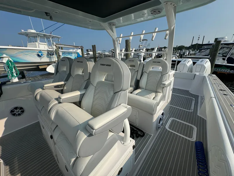 Slide: The Image of 2025 Twin Vee 400 GFX boat interior with luxurious seating at a marina. - 16