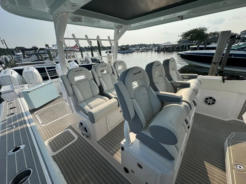 Slide: The Image of 2025 Twin Vee 400 GFX boat interior with luxurious seating at a marina. - 17