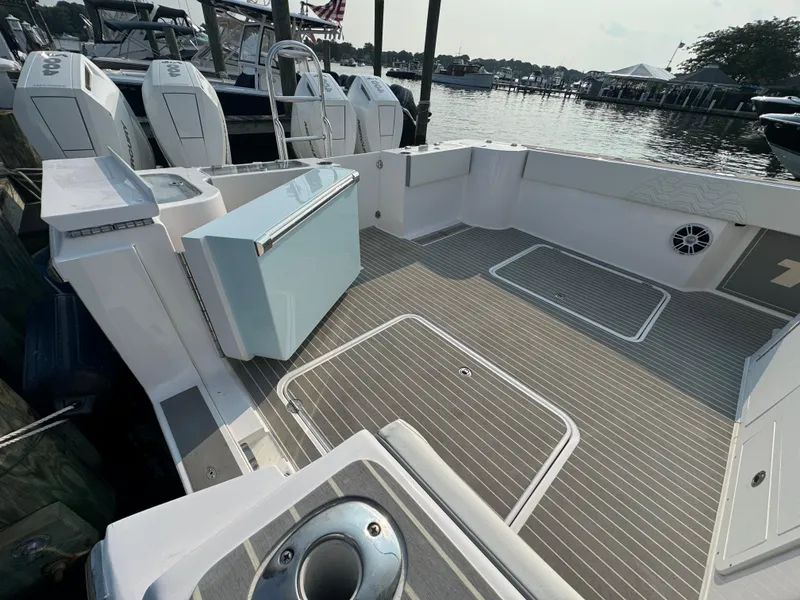 Slide: The Image of 2025 Twin Vee 400 GFX boat deck with storage compartments and outboard motors at a marina. - 20